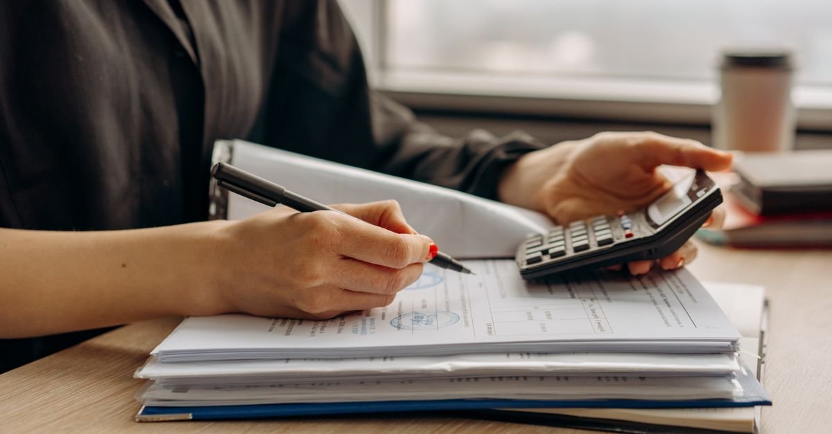 Hands using a calculator over paperwork at a desk