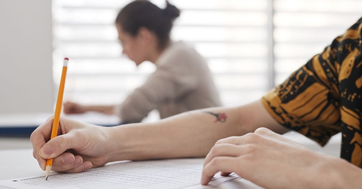 Close up of hands writing on an exam paper at a desk