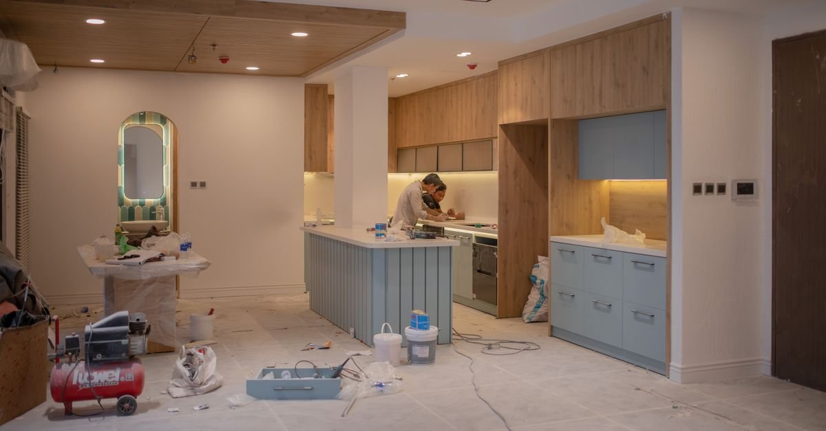Kitchen stripped back mid renovation with a worker and tools, work that needs a licensed contractor