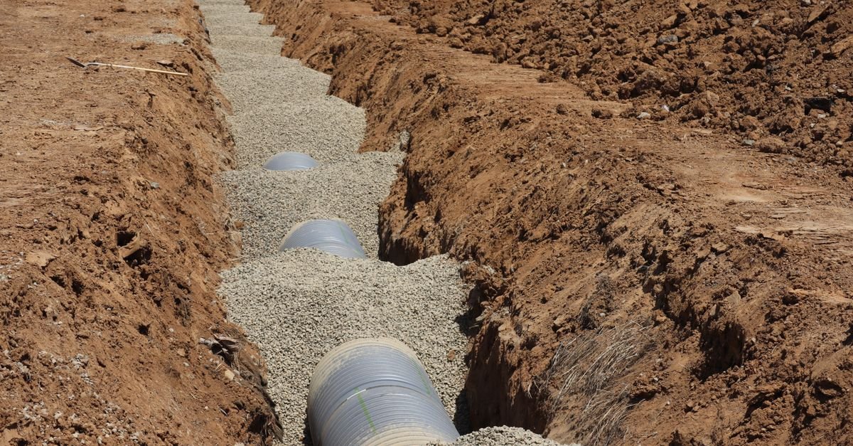 Irrigation pipe bedded in gravel inside an open trench on a Florida site needing a license