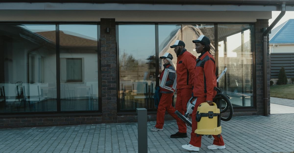 Grounds crew in orange overalls carrying equipment outside a home, the audience for irrigation licensing