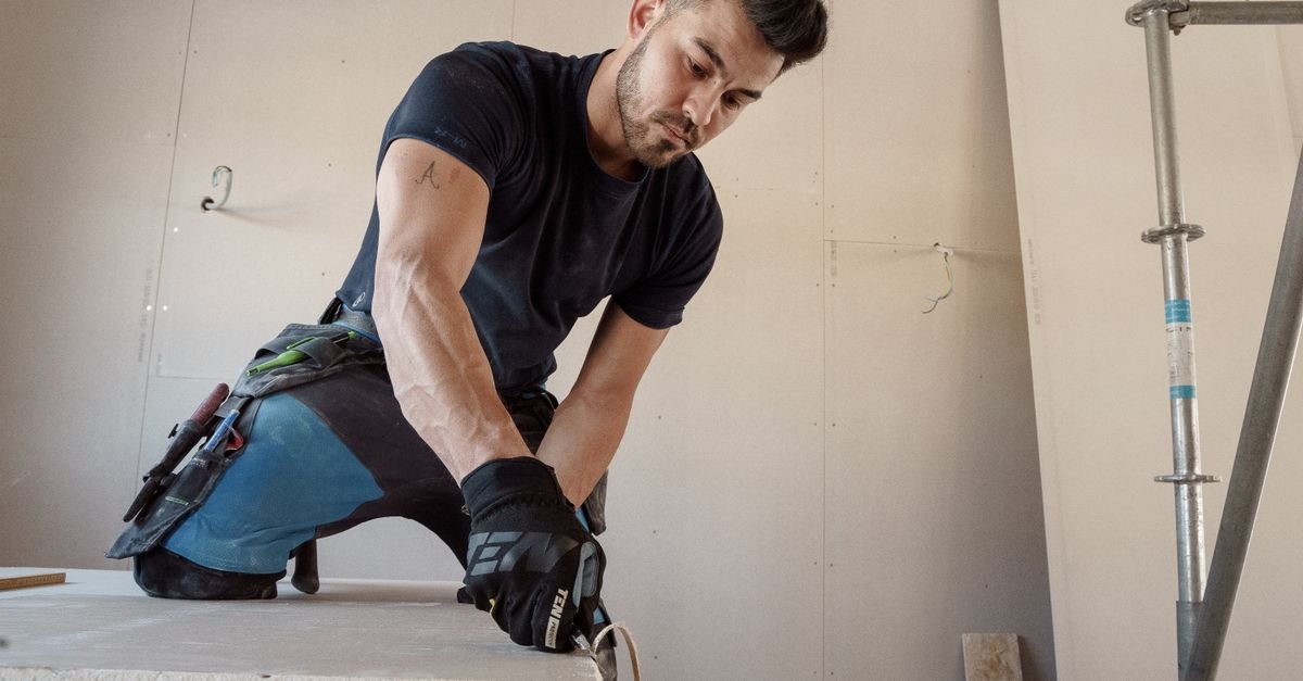 Worker in gloves cutting drywall on site, a trade Miami Dade licenses that Florida does not