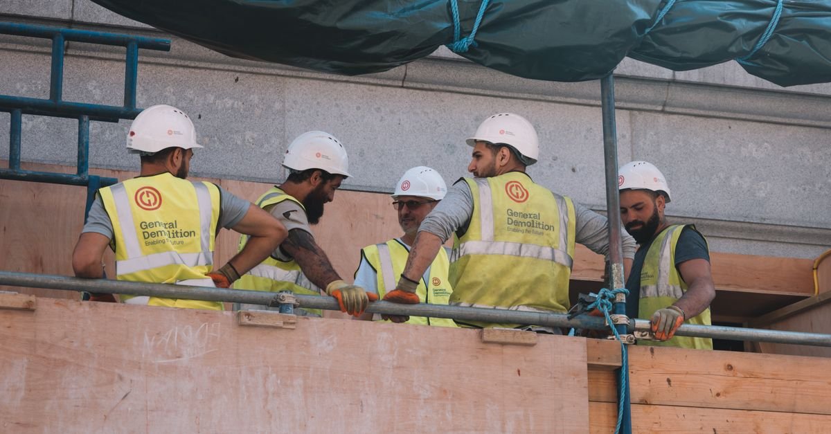 Crew in hard hats and high visibility vests talking on scaffolding, trade work the NASCLA exam tests lightly