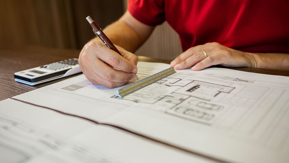 Working through a building floor plan with a scale ruler and calculator