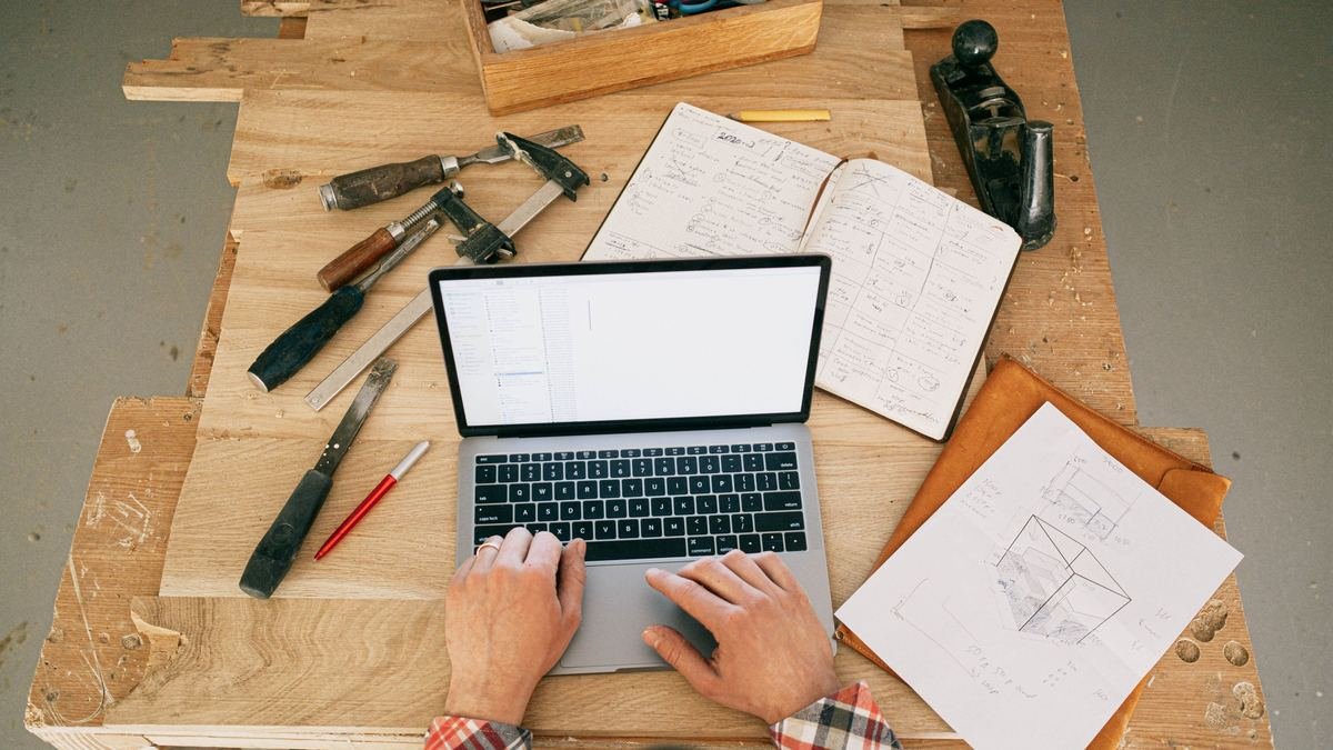 Studying for the contractor exam at a workbench - laptop, notes and hand tools